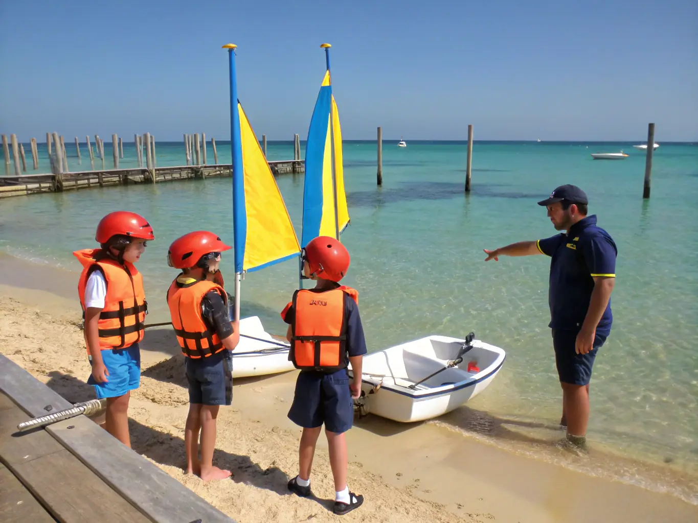 A photograph of children participating in a sailing lesson on a doris boat, with experienced instructors guiding them, showcasing accessible sports and youth engagement.
